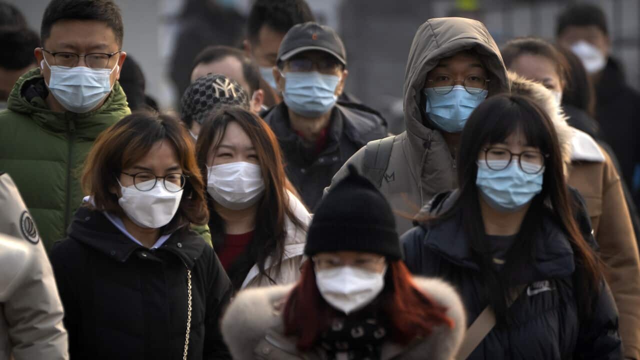 People wearing masks walk in a city.