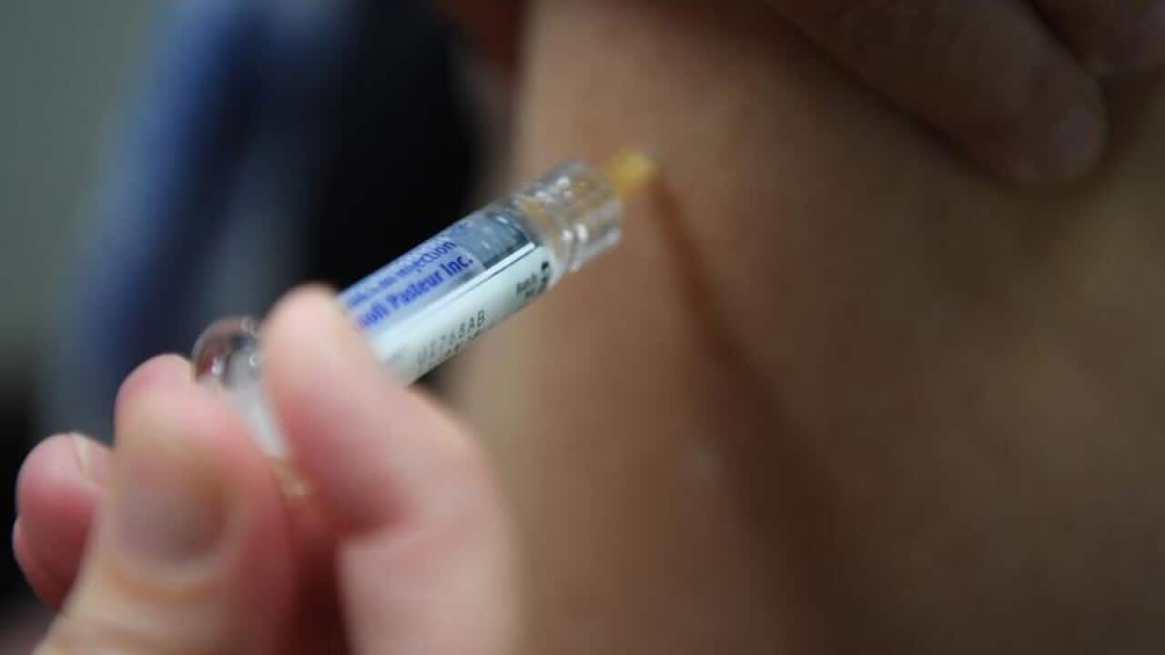 A woman is seen receiving a flu immunisation.