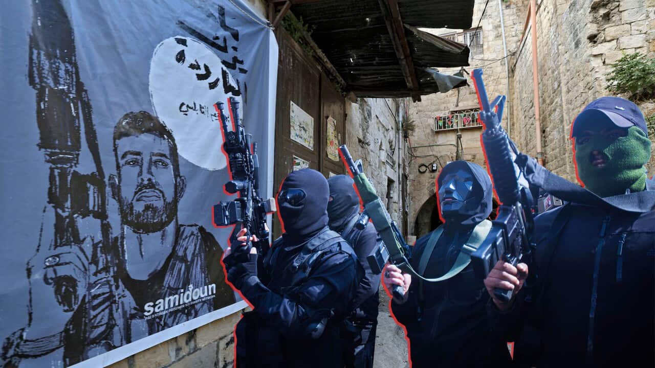 A poster of a bearded man with a ride hanging on a wall and four armed men wearing balaclavas
