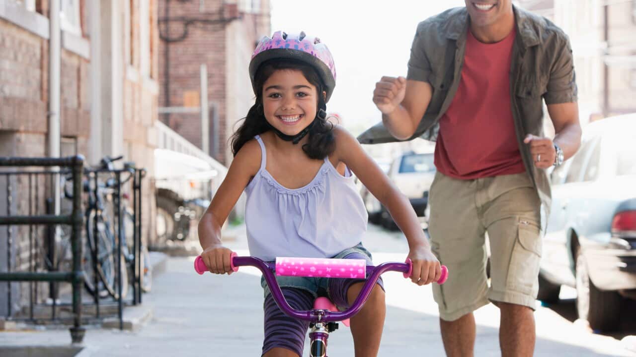Father teaching daughter to ride bicycle