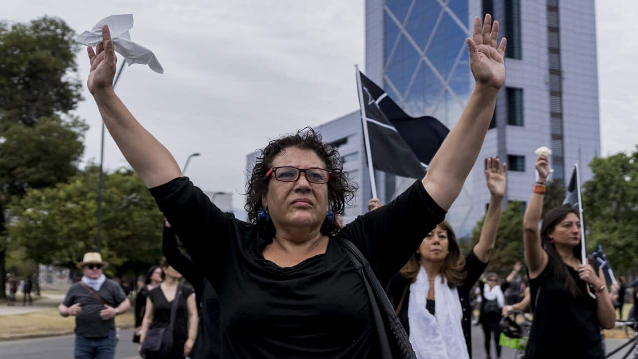 Women walk with their arms raised and dressed in black during a silent protest against the government of President of Chile Sebastián Piñera.