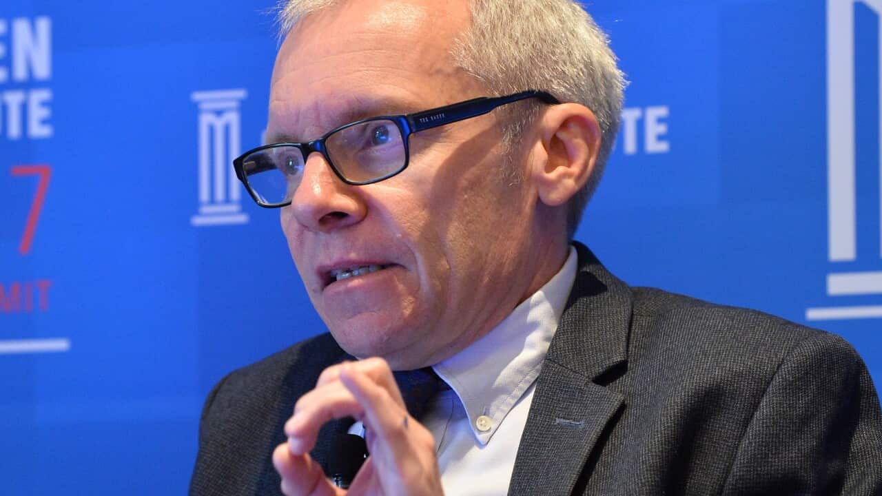 A man who is wearing a suit and tie sitting down and speaking.
