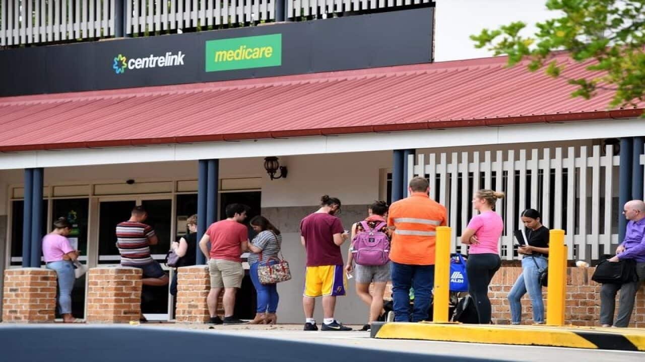 People are seen in a long queue outside a Centrelink office