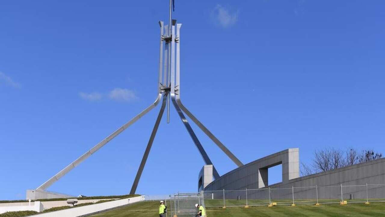 Workers put up a temporary fence on Parliament House