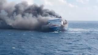A ship in open sea with smoke billowing from the vessel.