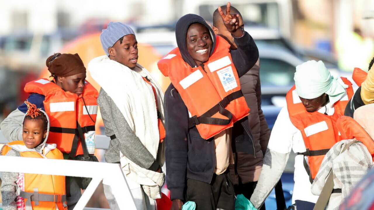 Migrants wave as they disembark at Pieta, Malta