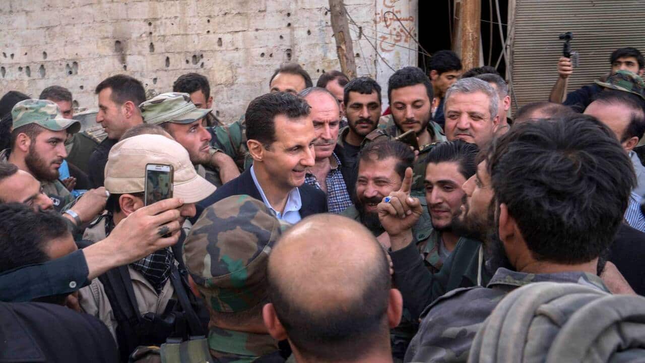 Syrian President Bashar Assad, center left, speaks with Syrian troops during a visit to the front line in the newly captured areas of eastern Ghouta.