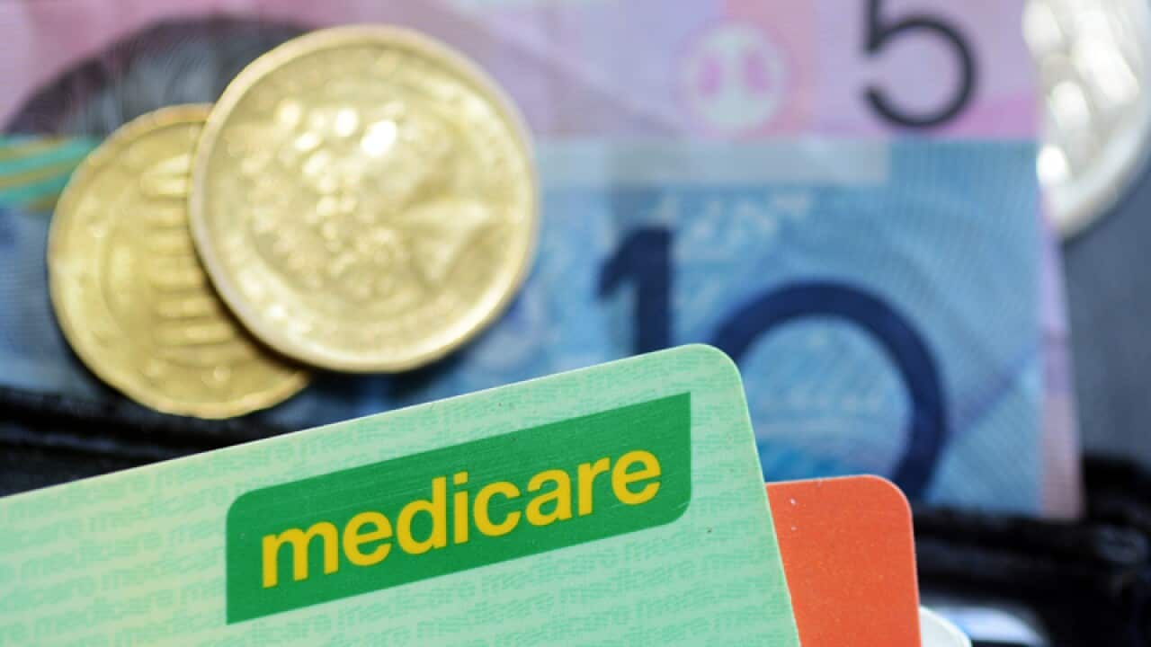 Bank notes and coins are seen with a Medicare card