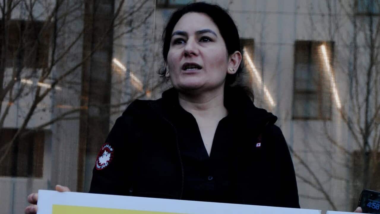 A woman holds a sign reading: "We deserve compassion".