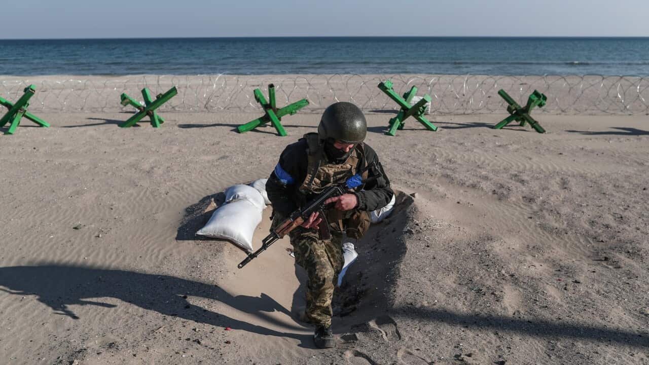 A Ukrainian soldier stands guard with his gun next to barricades at the beachfront in south Ukrainian city of Odesa