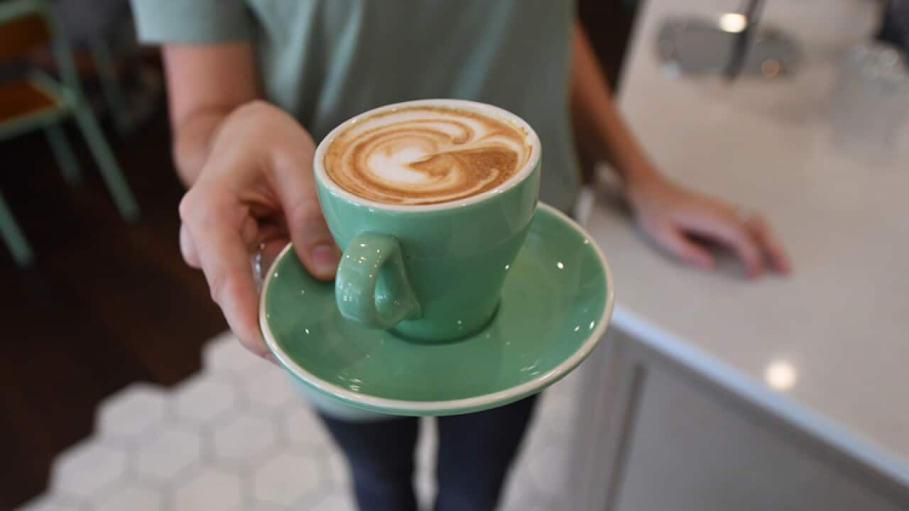 A waitress is seen holding a coffee at a cafe
