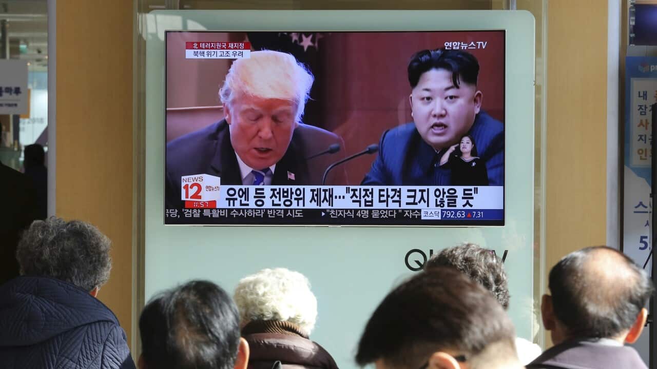 People watch a TV screen showing images of Donald Trump and Kim Jong Un in Seoul.