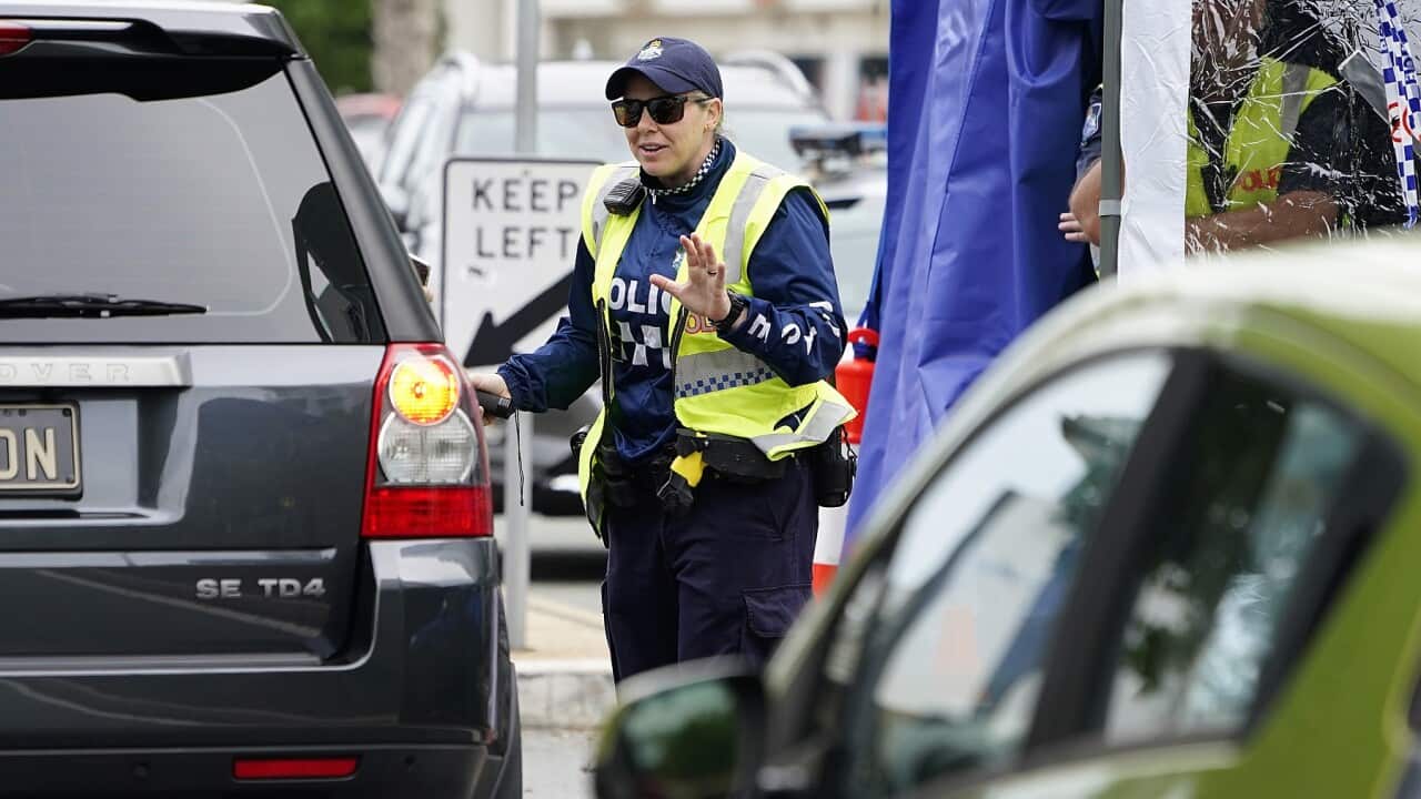 A Queensland police officer stops a motorist at a checkpoint at Coolangatta on the Queensland-New South Wales border, Friday, May 22, 2020. (AAP Image/Dave Hunt) NO ARCHIVING