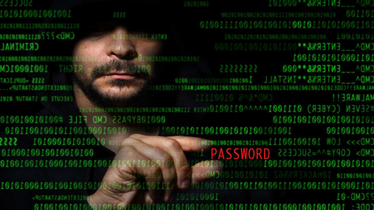 An unidentified man looking at coding with the word PASSWORD in red.