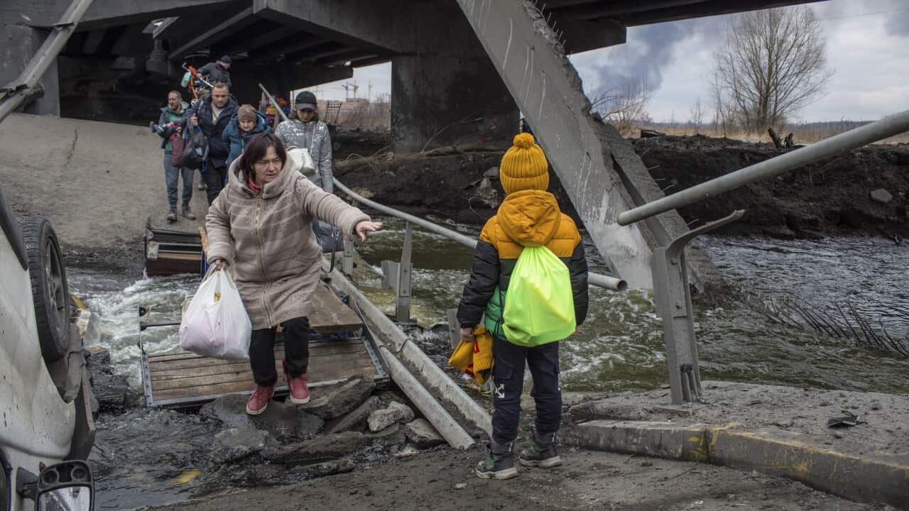 Civilians cross amid rubble of a damaged bridge in the Irpin city near from Kyiv