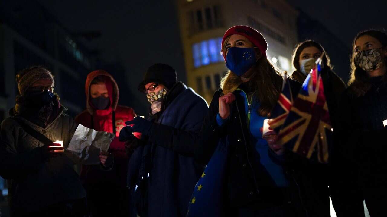 British citizens, who live in Belgium, hold candles and Union flags during an anti-Brexit vigil in Brussels on 31 December, 2020. 