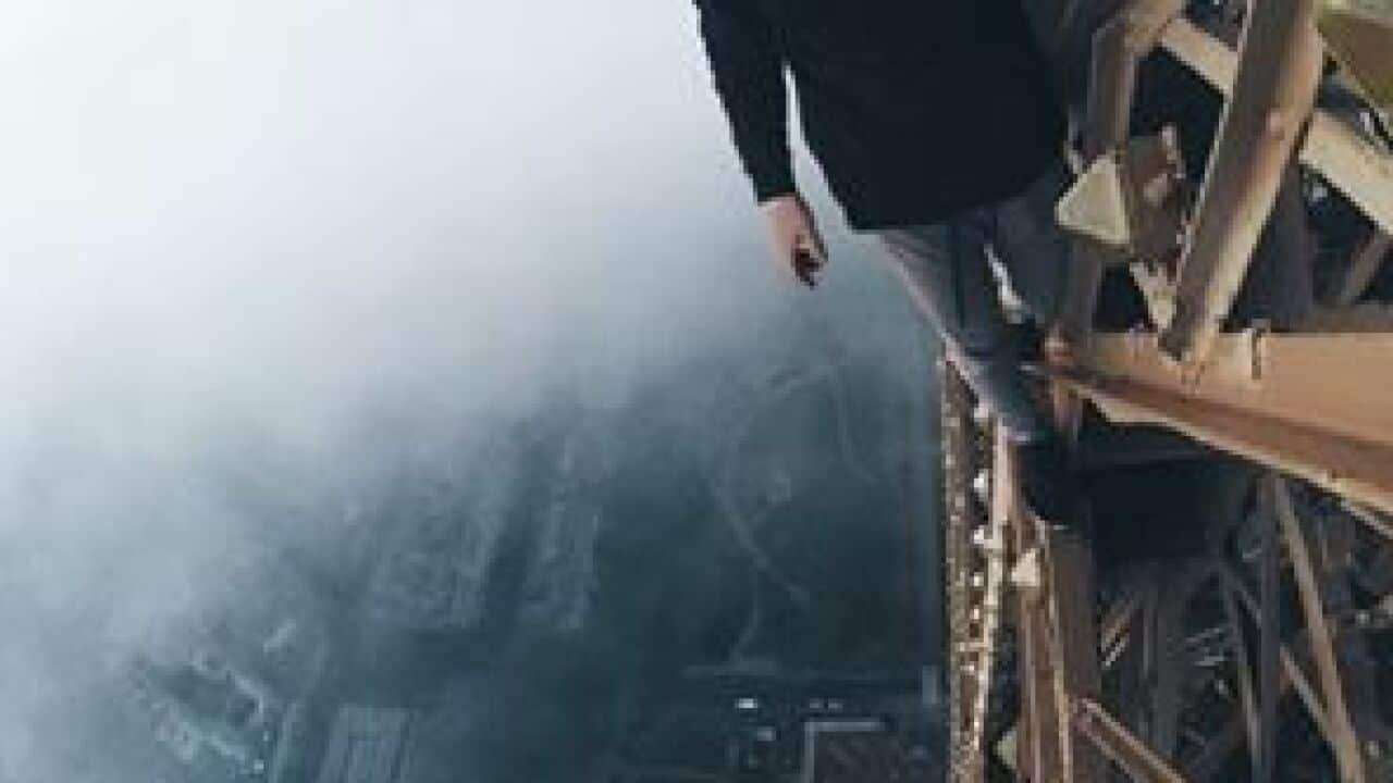 A Russian man looks down from the framework of the Eiffel Tower.