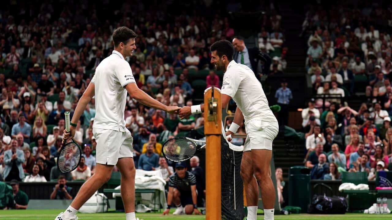 Novak Djokovic and Hubert Hurkacz smile and shake hands after Djokovic collided with the net during their 4th round match at the 2023 Wimbledon