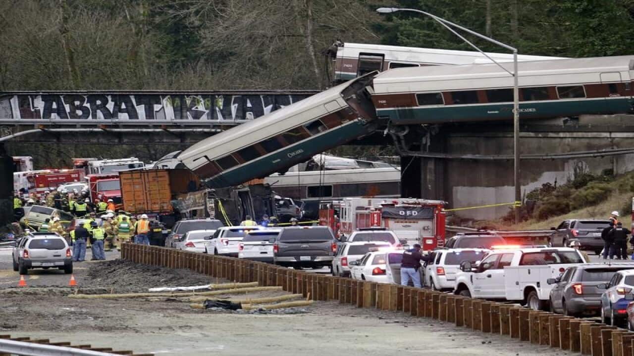 Cars from an Amtrak train lay spilled onto Interstate