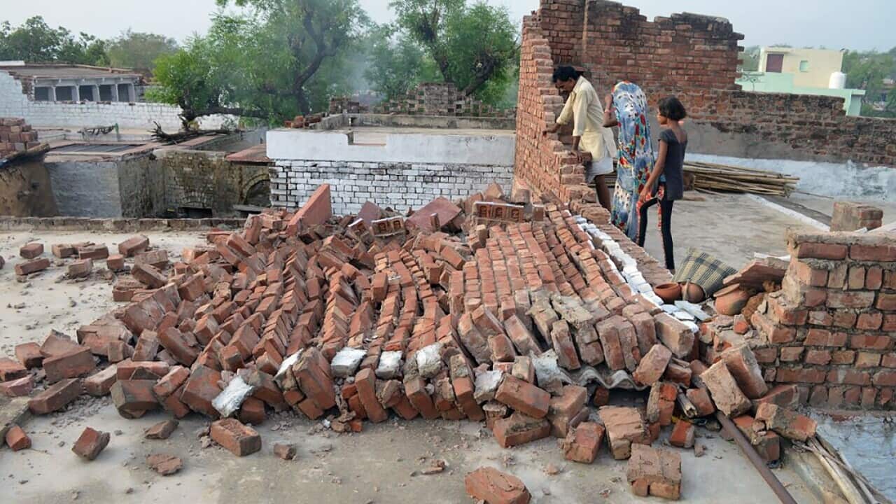 Indian residents look at a wall damaged by high winds during a major dust storm in Agra, India.