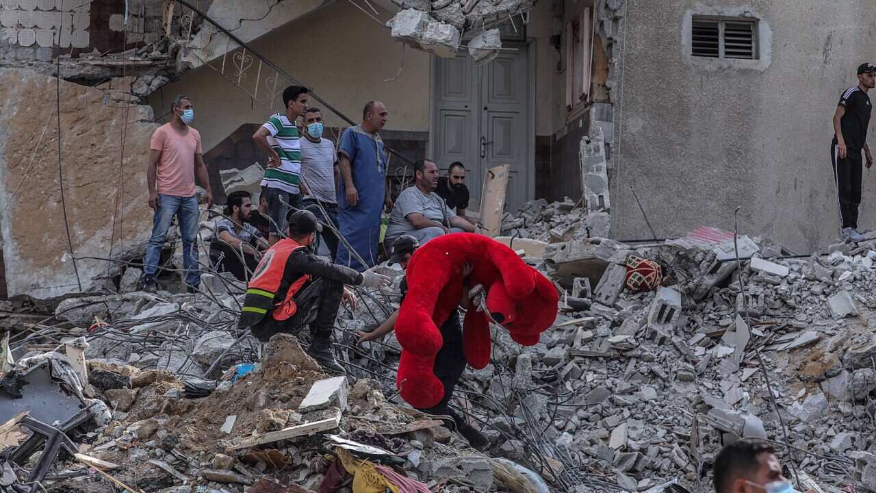A Palestinian holds a teddy bear from the rubble of a destroyed houses after an Israeli air strike in Gaza City on, 16 May 2021.