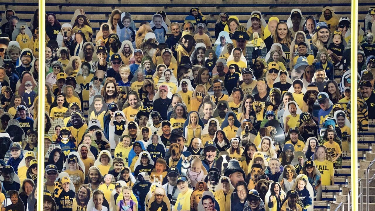 Cardboard cutouts of people sit in the stands in Michigan Stadium