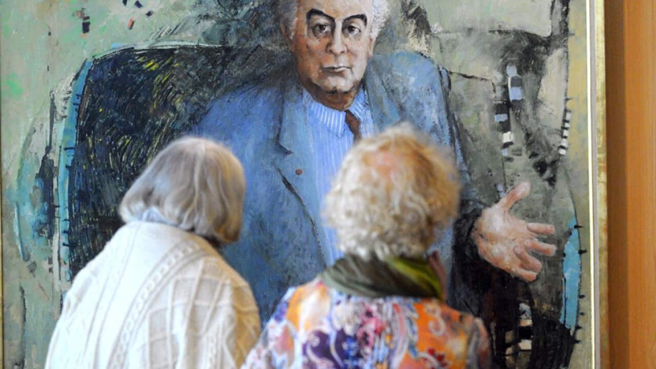 Visitors inspect the portrait of former Prime Ministers Gough Whitlam