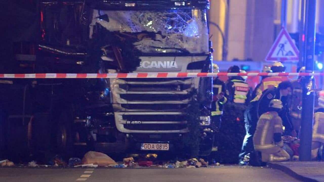 Rescue workers inspect the scenes and the truck that crashed into a Christmas market, close to the Kaiser Wilhelm memorial church in Berlin