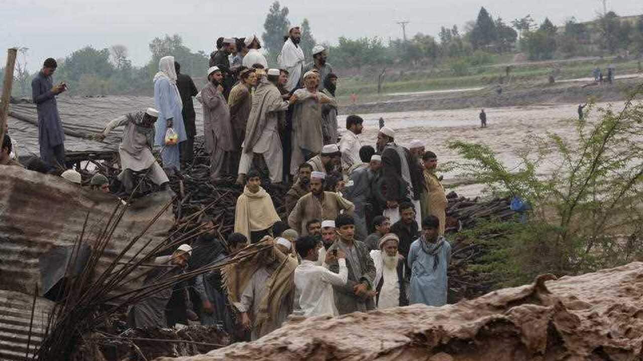 Pakistani villagers stand on a high vantage point surrounded by flash flooding on the outskirts of Peshawar, Pakistan, Sunday, April 3, 2016.