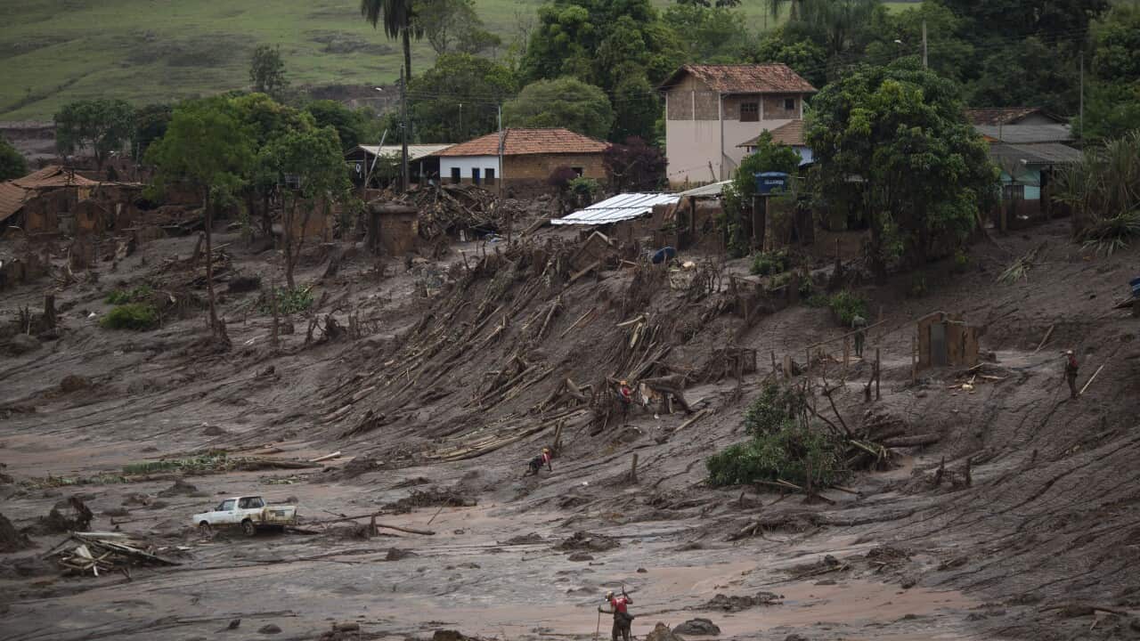 Rescue workers walk at the site where the town of Bento Rodrigues stood after two dams burst