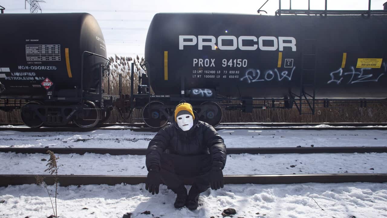 A protestor sits on train tracks during a blockade of a rail line in Canada