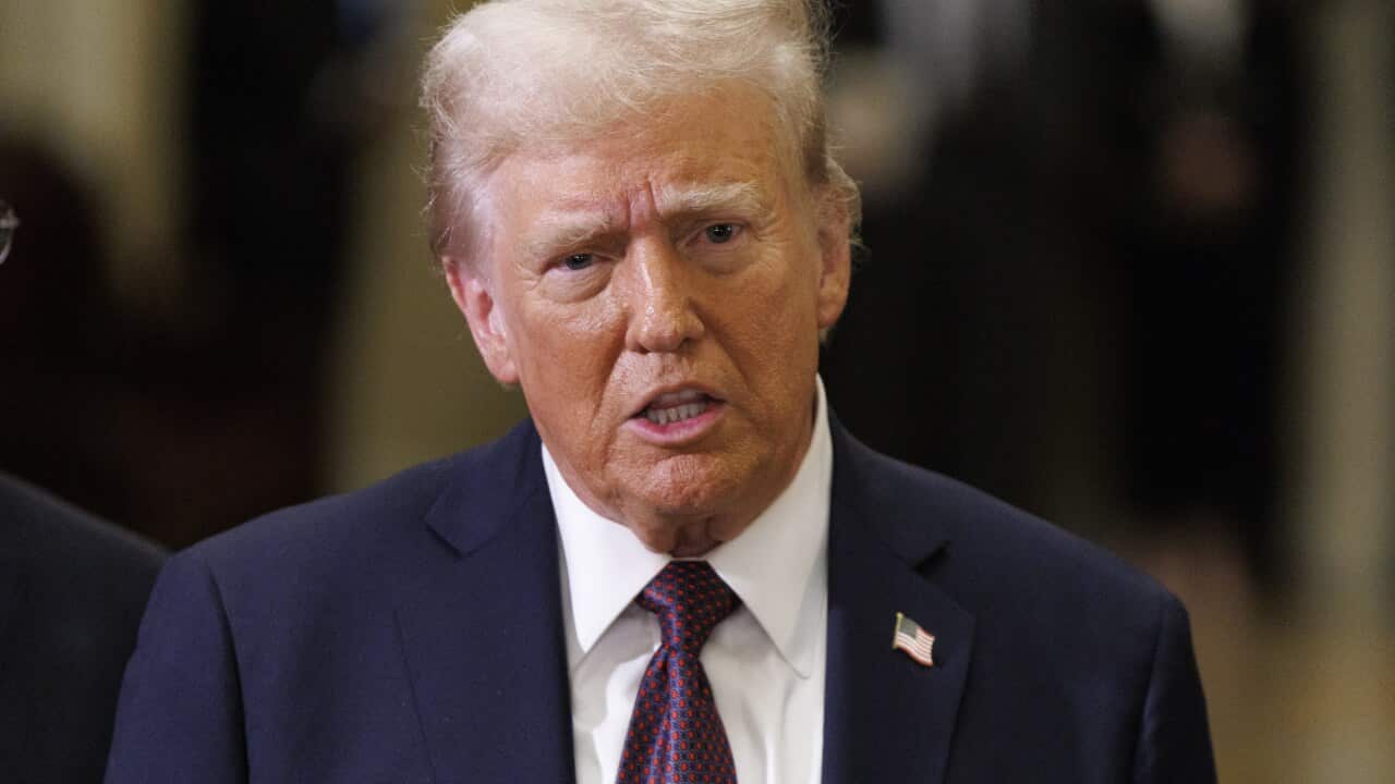 Donald Trump in a navy suit wearing an American flag pin.