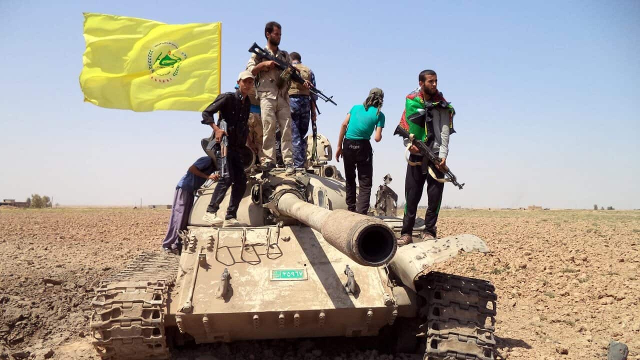Members of the Iraqi Shiite militia, Kataib Hezbollah, stand over a tank during fighting against Islamic State in September 2014.