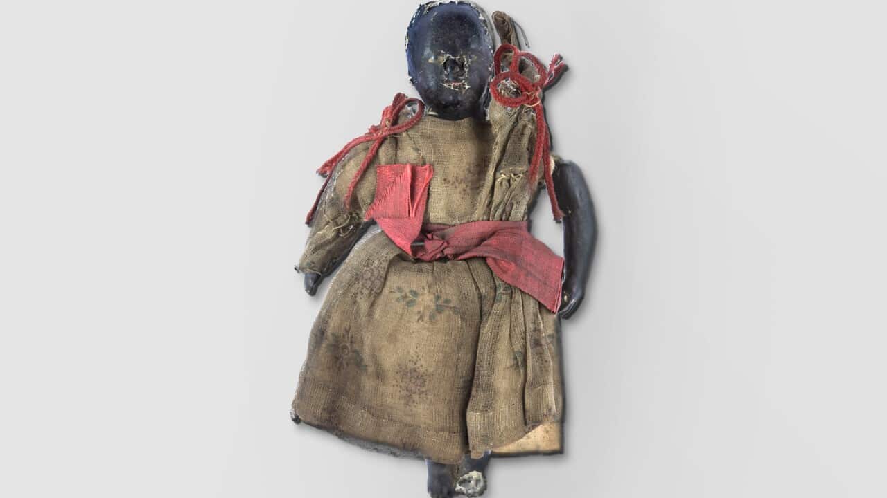 A black doll in a dress with red bows