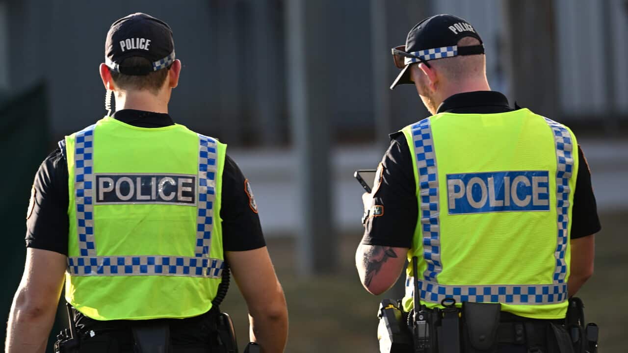 Two police officers with their backs turned to the camera in yellow vests