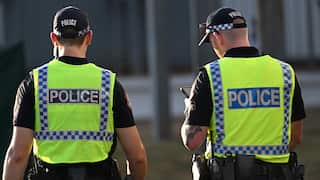 Two police officers with their backs turned to the camera in yellow vests