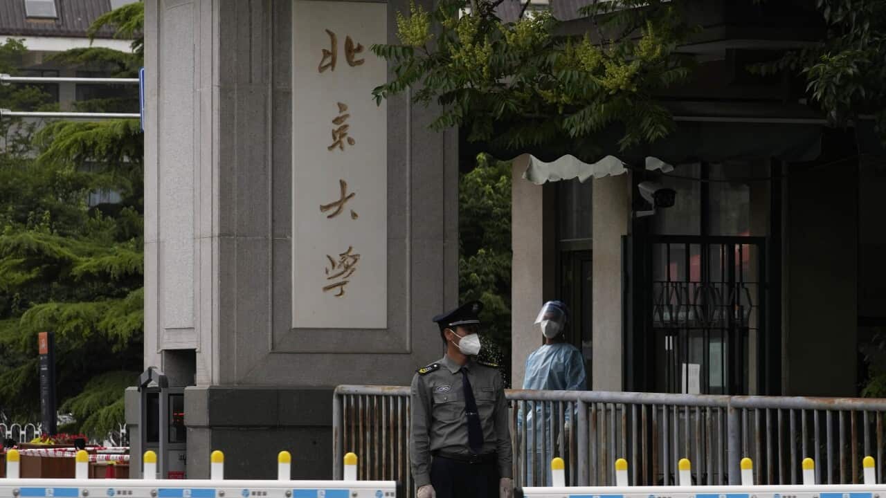 FOR USE WITH STORY VIRUS OUTBREAK CHINA STUDENT PROTEST A security guard and a pandemic worker stand guard near the words Peking University at one of the entrance to the main campus of Peking University on Tuesday, May 17, 2022, in Beijing. Administrators