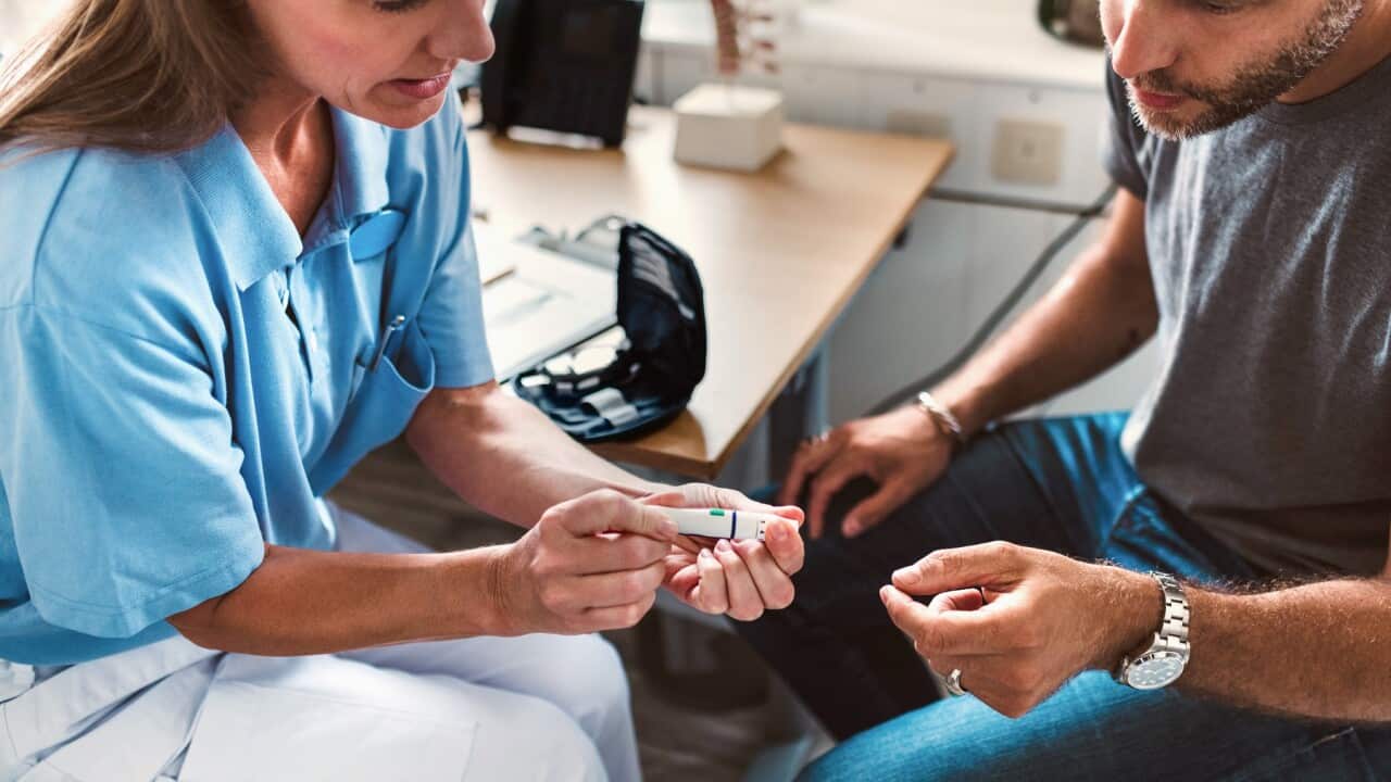 High angle view of nurse holding medical equipment while explaining to patient at clinic