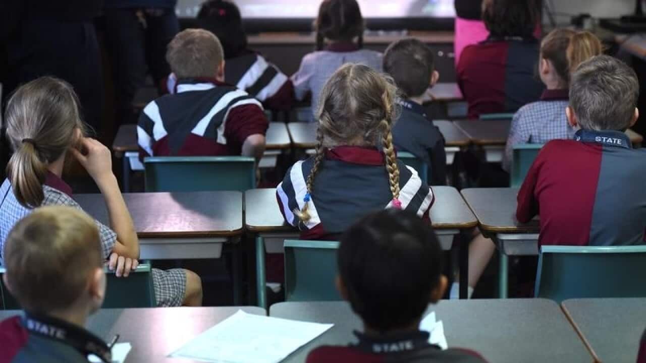 Children sit in a classroom during a lesson.