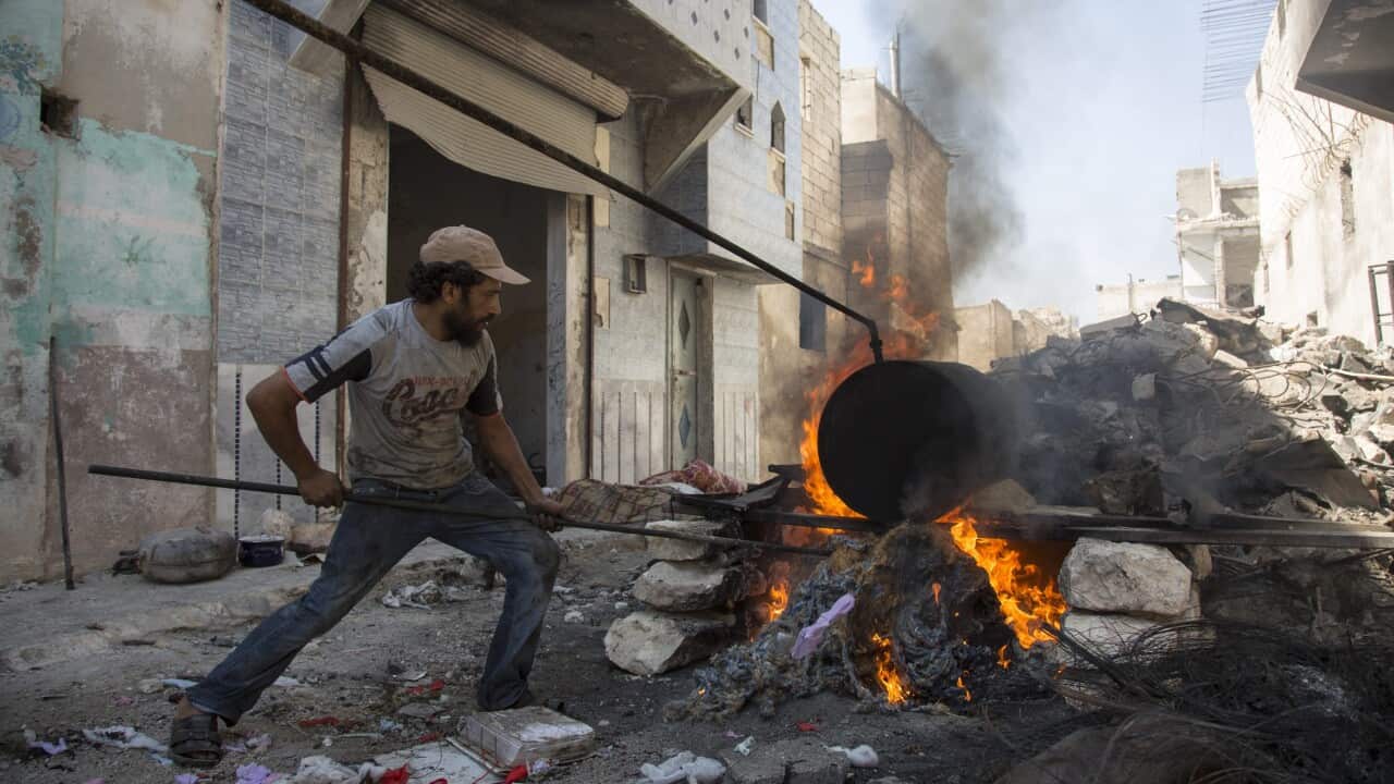 A picture made available on 11 September 2016 shows a Syrian man stoking a fire as he converts plastic into fuel in the outskirts of Aleppo.