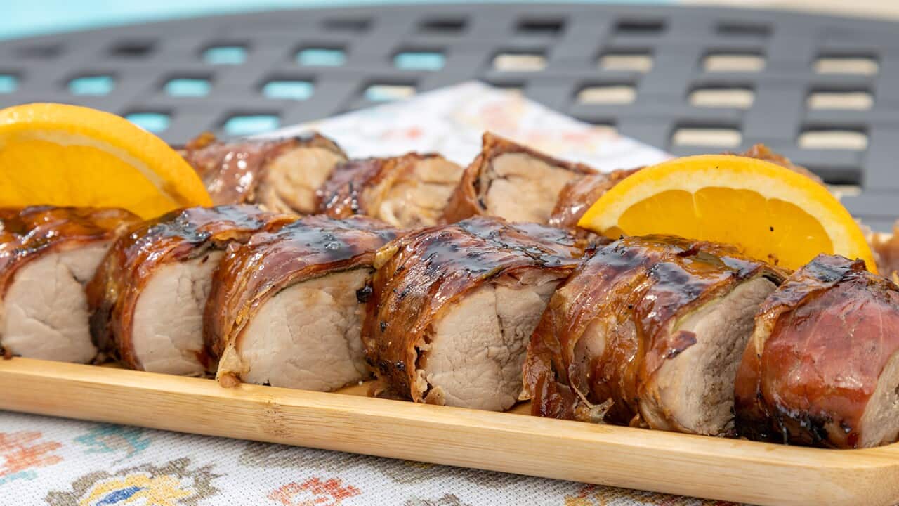 Thick round slices of pork with a crisp coating sit on a long tray.