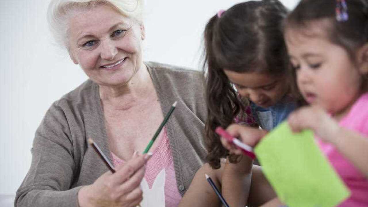 Woman helping granddaughters with craft