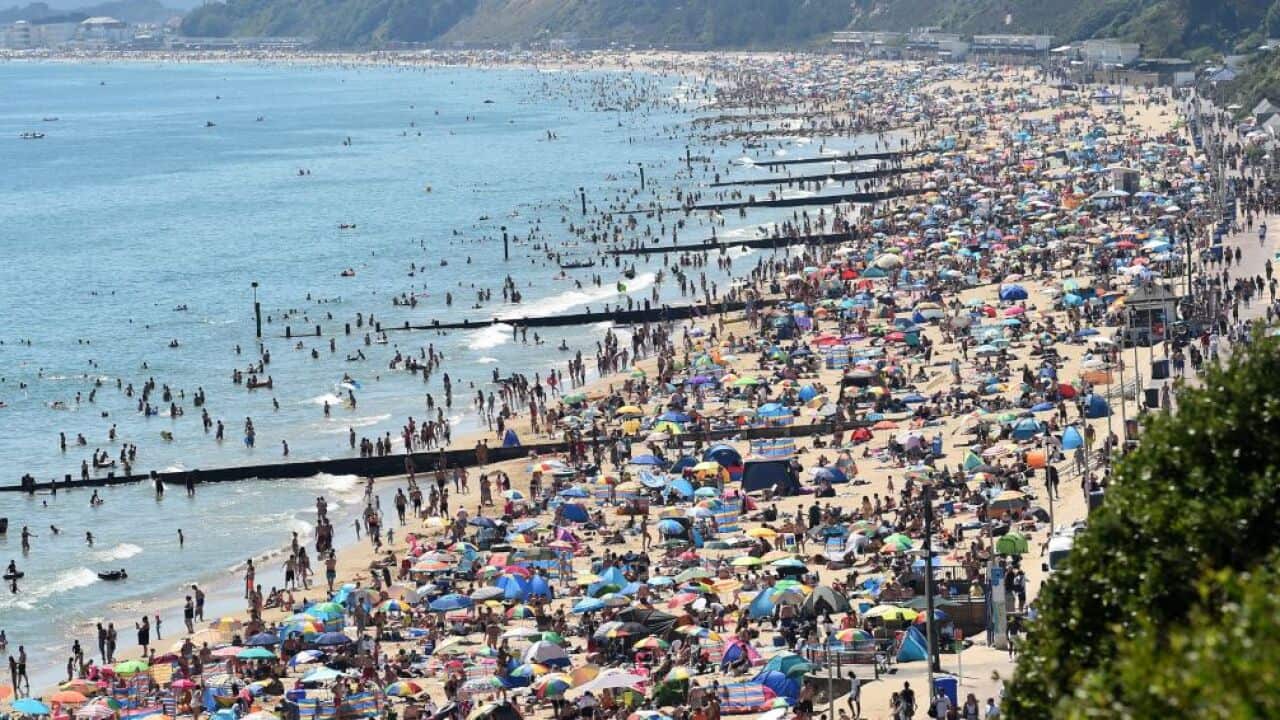Beachgoers enjoy the sunshine as they sunbathe and play in the sea on Bournemouth beach in southern England.