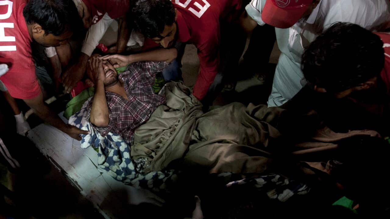 Pakistani rescue workers and volunteers unload an injured victim of bomb blast at a Sufi shrine, from an ambulance