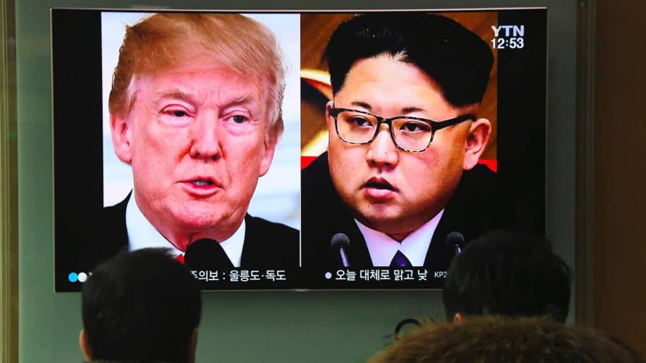 People watch a television news report showing pictures of US President Donald Trump (L) and North Korean leader Kim Jong Un at a railway station in Seoul.