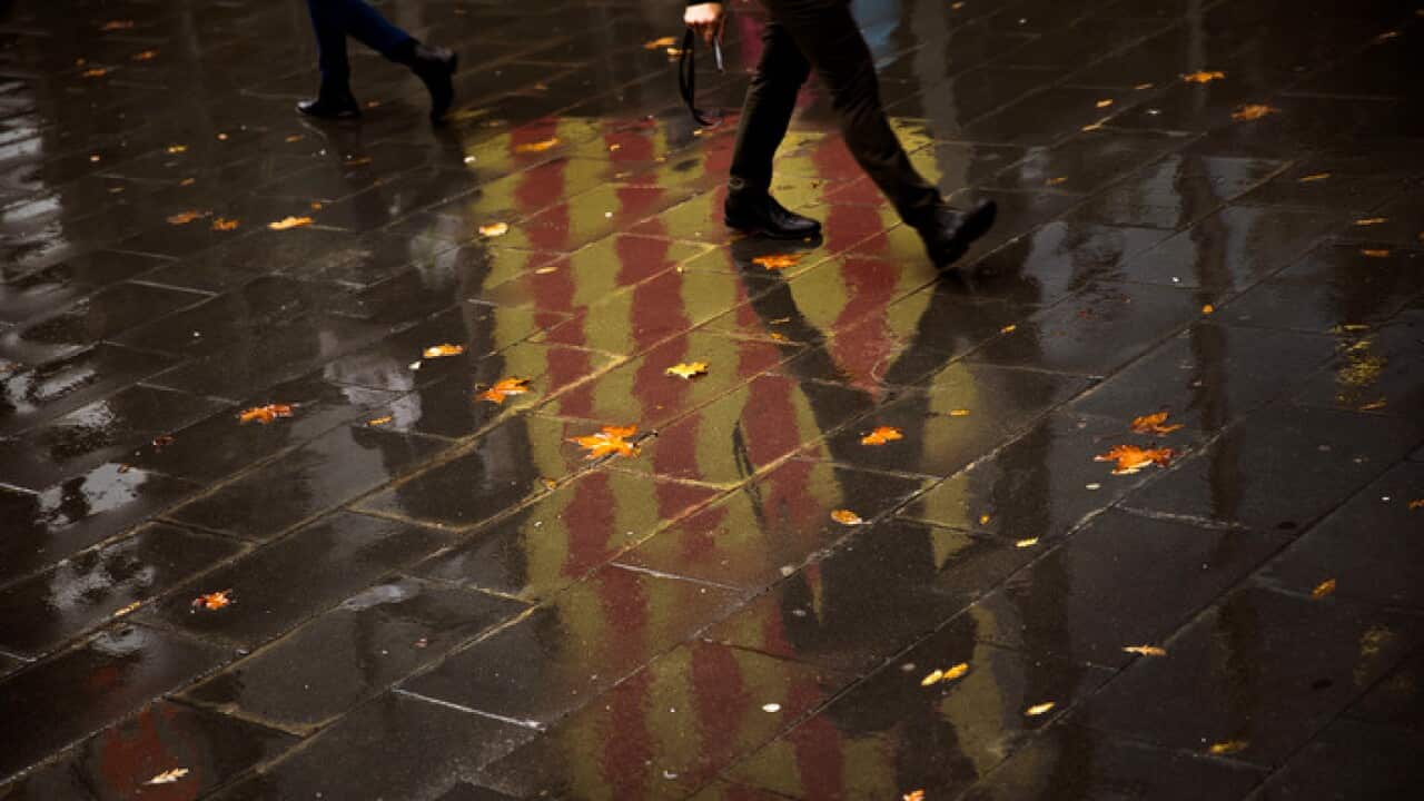 People walk past a Catalan flag reflected on the ground in Barcelona, Spain,