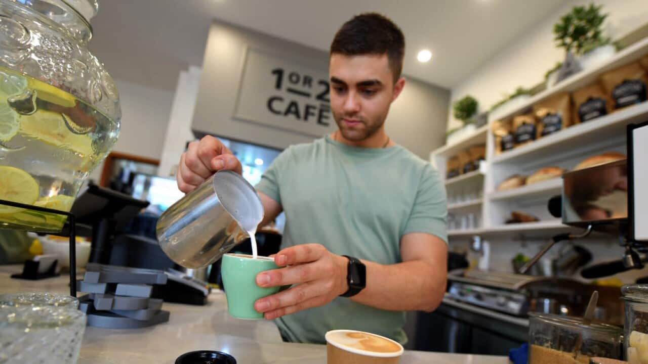 A barista working at a coffee machine at a cafe in Canberra