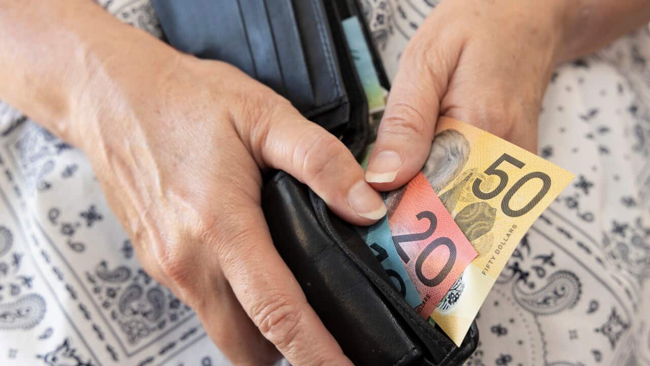 Hands holding a wallet with cash in it.