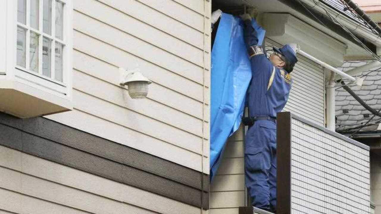 A police officer places a blue sheet on part of an apartment house in Zama, Kanagawa Prefecture on Oct. 31, 2017 where police found nine dismembered bodies in one of its units. The apartment is the home of 27-year-old Takahiro Shiraishi.