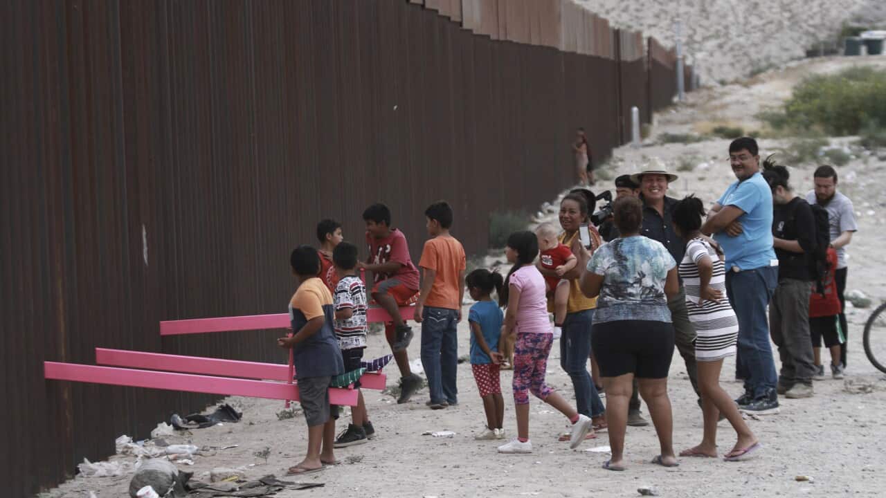 Kids plays on a seesaw installed between the steel fence that divides Mexico from the United States.